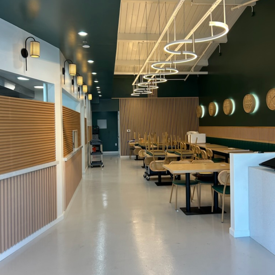 Interior of Jack's Bao restaurant with dark green walls, light wood accents, and modern circular lighting.