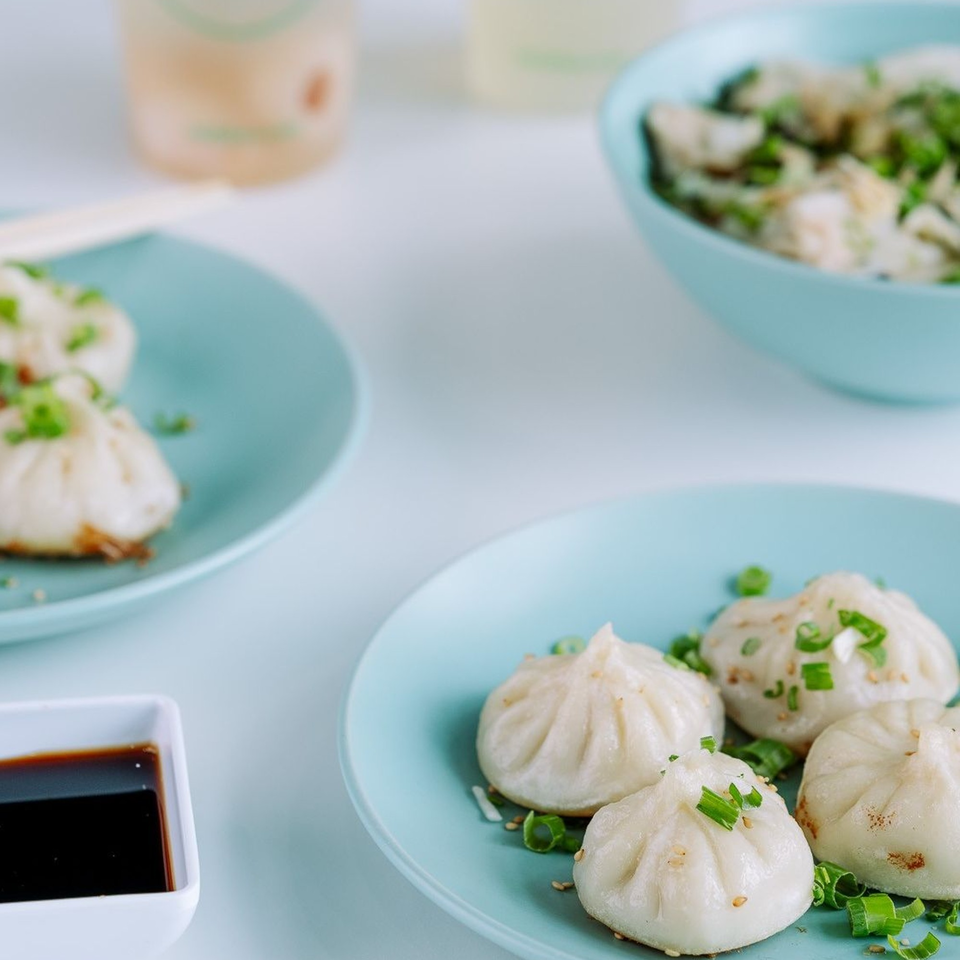 Plates of Jack's Bao dumplings, garnished with green onions and sesame seeds, with soy sauce.