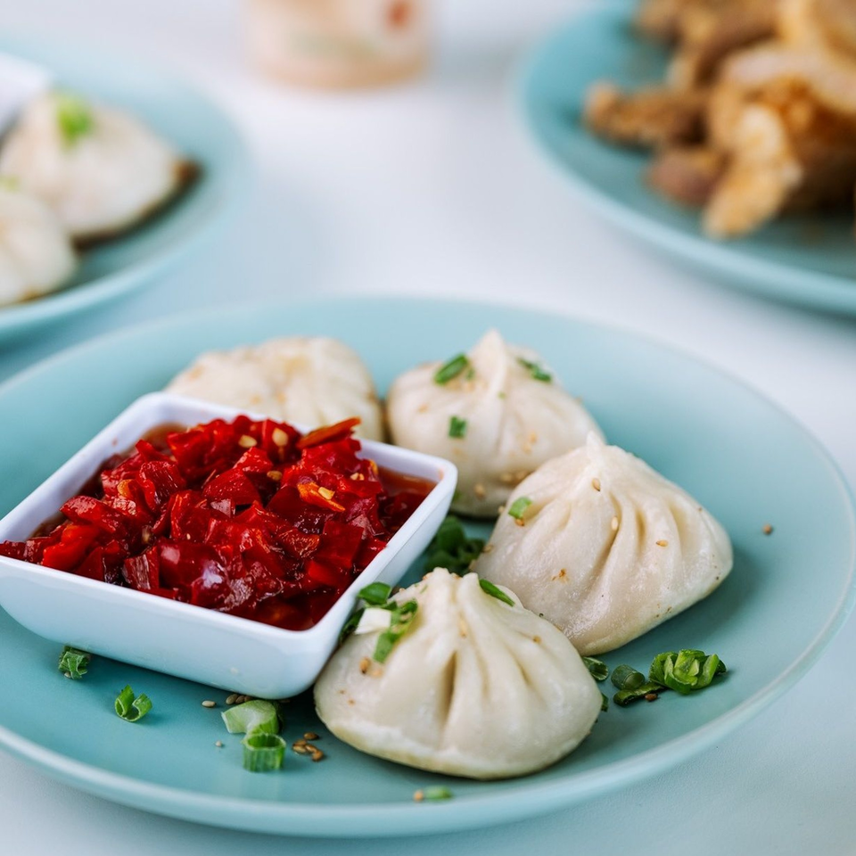 Jack's Bao dumplings with red chili sauce, garnished with green onions and sesame seeds.