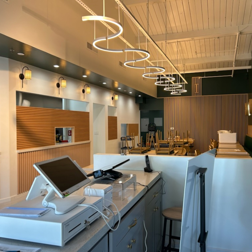 The interior of Jack's Bao restaurant, featuring a modern counter, wooden slat walls, and stacked chairs.